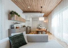 北欧テイストでコーディネートされたLDK。天井に木目調のクロスを貼って温かみを出した。カーテンを開けると中庭とつながる