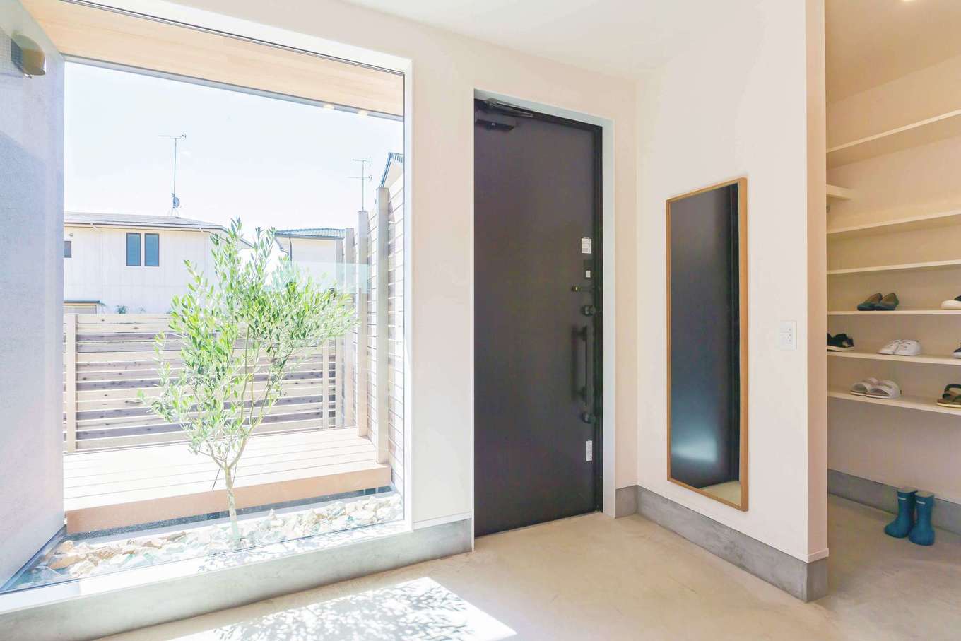 ARRCH アーチ【デザイン住宅、間取り、建築家】室内から眺めた玄関。南面に面しているので、大きな固定窓を設けて明るさと開放感を確保した