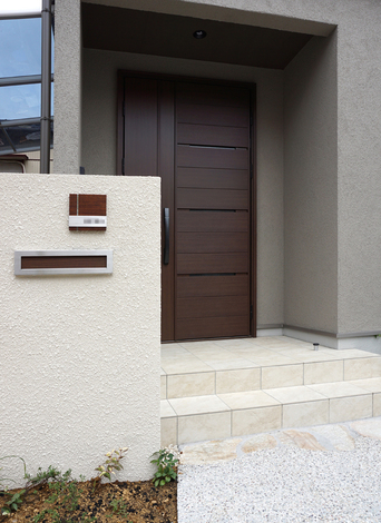 親世帯の玄関ドアとはデザインが異なりつつも、色味を合わせて統一感を持たせている