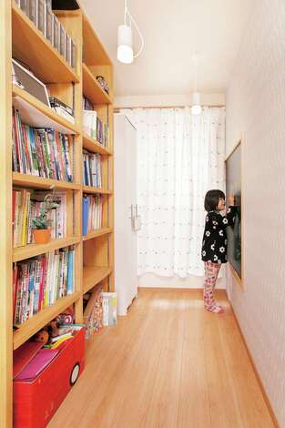 バルコニーに出る2階フロアの廊下は本棚を造作してライブラリーに。黒板ボードを取り付けてお絵かきコーナーも誕生