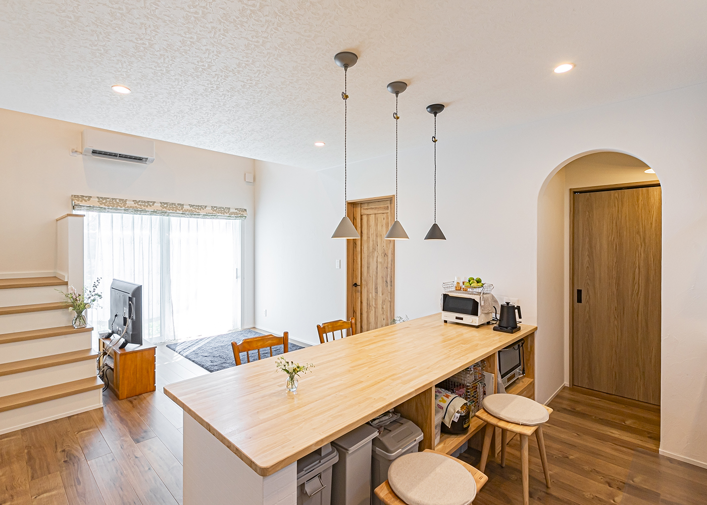 cozy house（小塚建設）【二世帯住宅、間取り、平屋】キッチンの造作カウンターは、収納も兼ねている。アーチの向こうはパントリー。さらにランドリールームに続く