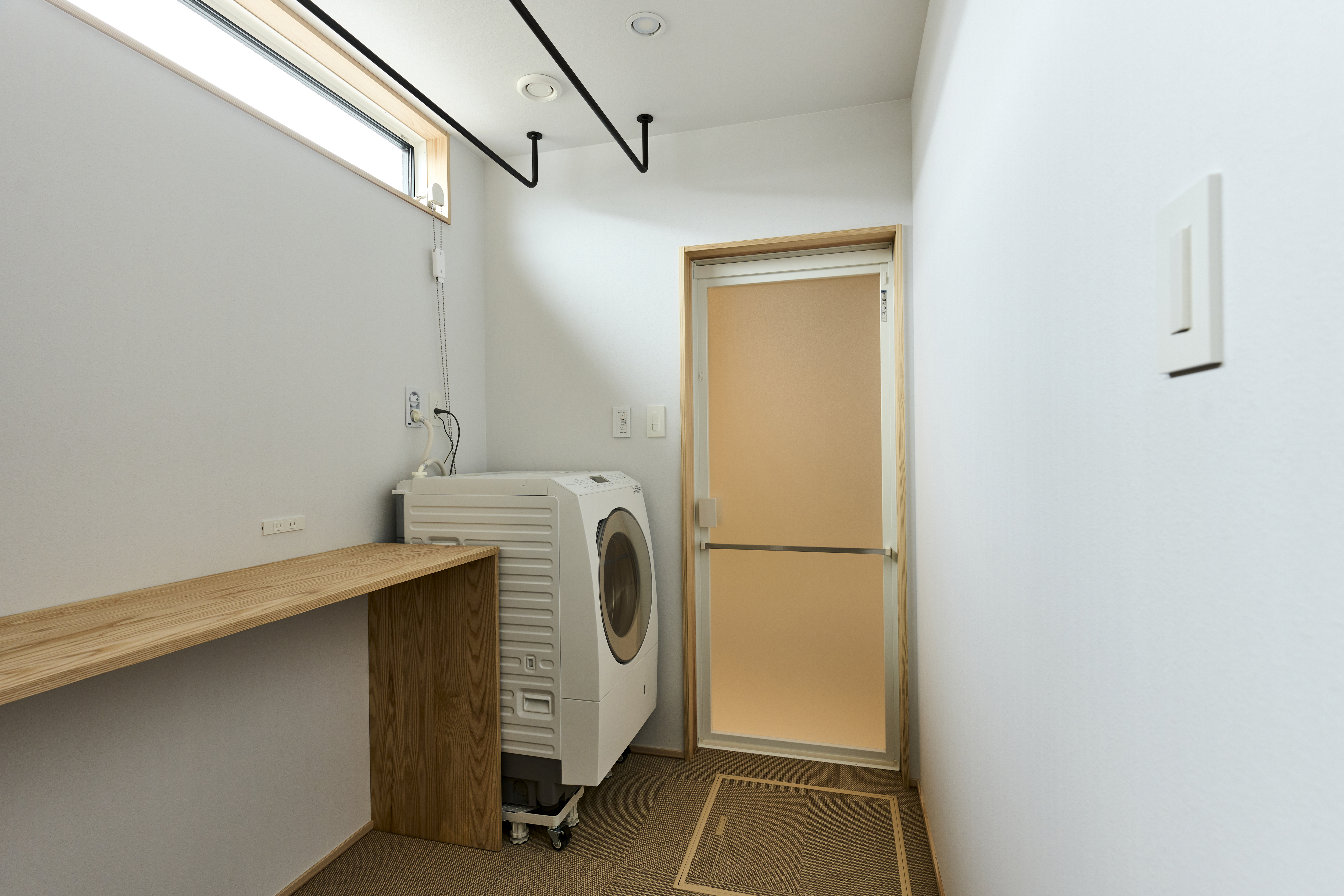 KEN建築工房｜シンプルで機能的なランドリールーム。洗濯機と作業用のカウンターが設置されており、家事動線を考慮したスッキリとした印象です。