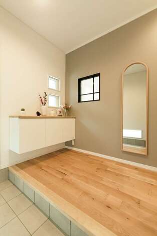 グレーのクロスに造作窓が映える玄関ホール。鏡の反射でより広く感じられる