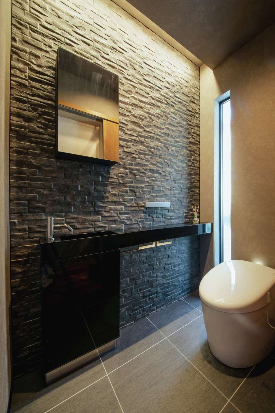 SEVEN HOUSE/セブンハウス【デザイン住宅、子育て、間取り】夫婦が特に気に入っている1階トイレ。玄関ホールと同じタイルを壁一面に張り、間接照明でホテルのような高級感を演出し、ゲストからも大好評