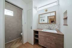 入浴中も使用できるように洗面は脱衣室から分離させた。洗面台は造作風の既製品を選択。タイルやオリジナルの三面鏡、ニッチなどのコーディネートにより、コストを抑えながら大満足の仕上がりに