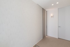 シンプルでモダンなデザインの玄関ホール。白を基調とした空間が広がり、壁面の間接照明が落ち着いた雰囲気を演出する。