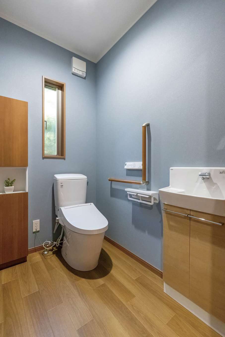 住まいるコーポレーション【自然素材、省エネ、間取り】玄関とお父さまの部屋から近い位置に設けたトイレ。車椅子のままでも入れる広さと手すりを設置したバリアフリー仕様になっている