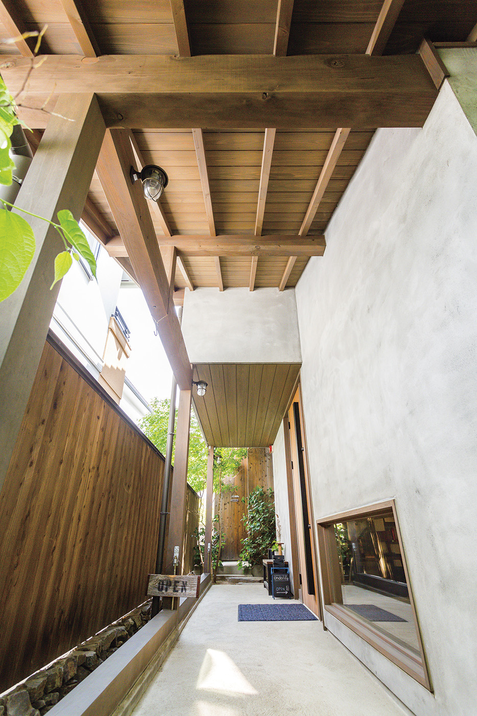 温戸ライフ【自然素材、間取り、インテリア】モルタルの壁と木の組み合わせで、落ち着いたプライベート感を確保した玄関アプローチ
