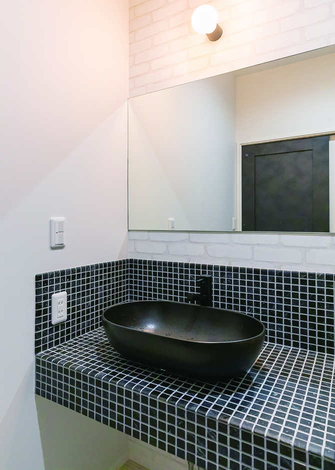 モノクロのタイルと黒のシンクが、印象的な造作洗面台。広いシンクで使い勝手も良い