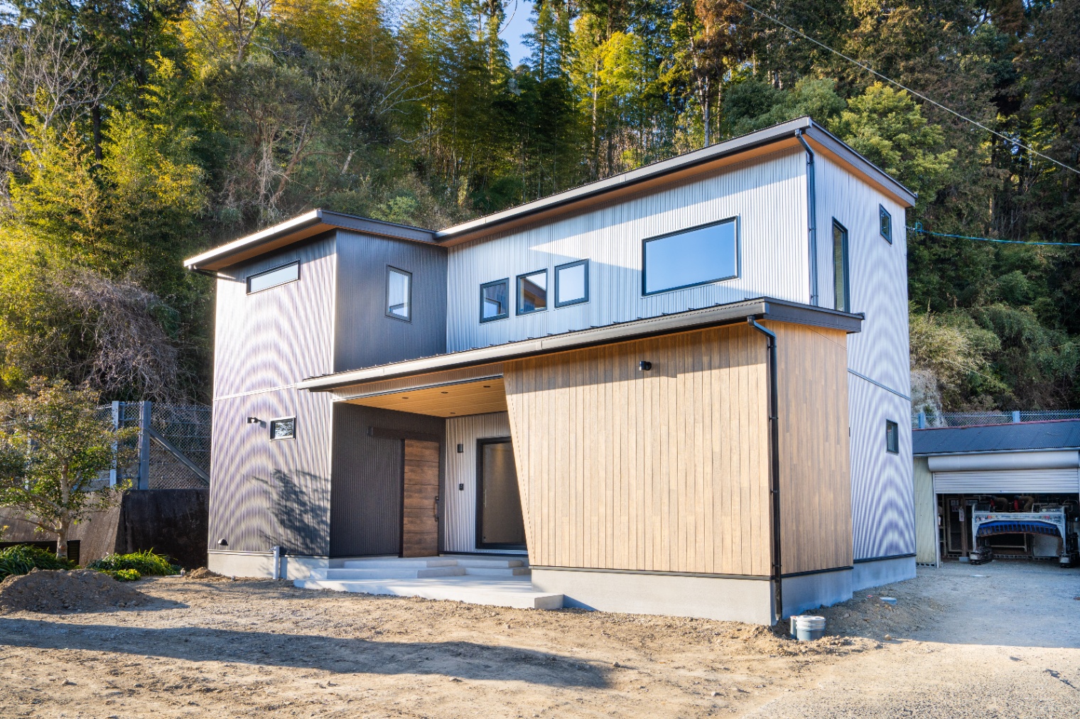 アイジーホーム｜木目とガルバリウムが調和するモダンな二階建ての住宅。周囲の自然と美しく融合し、遊び心のある住環境を提供するデザインである。