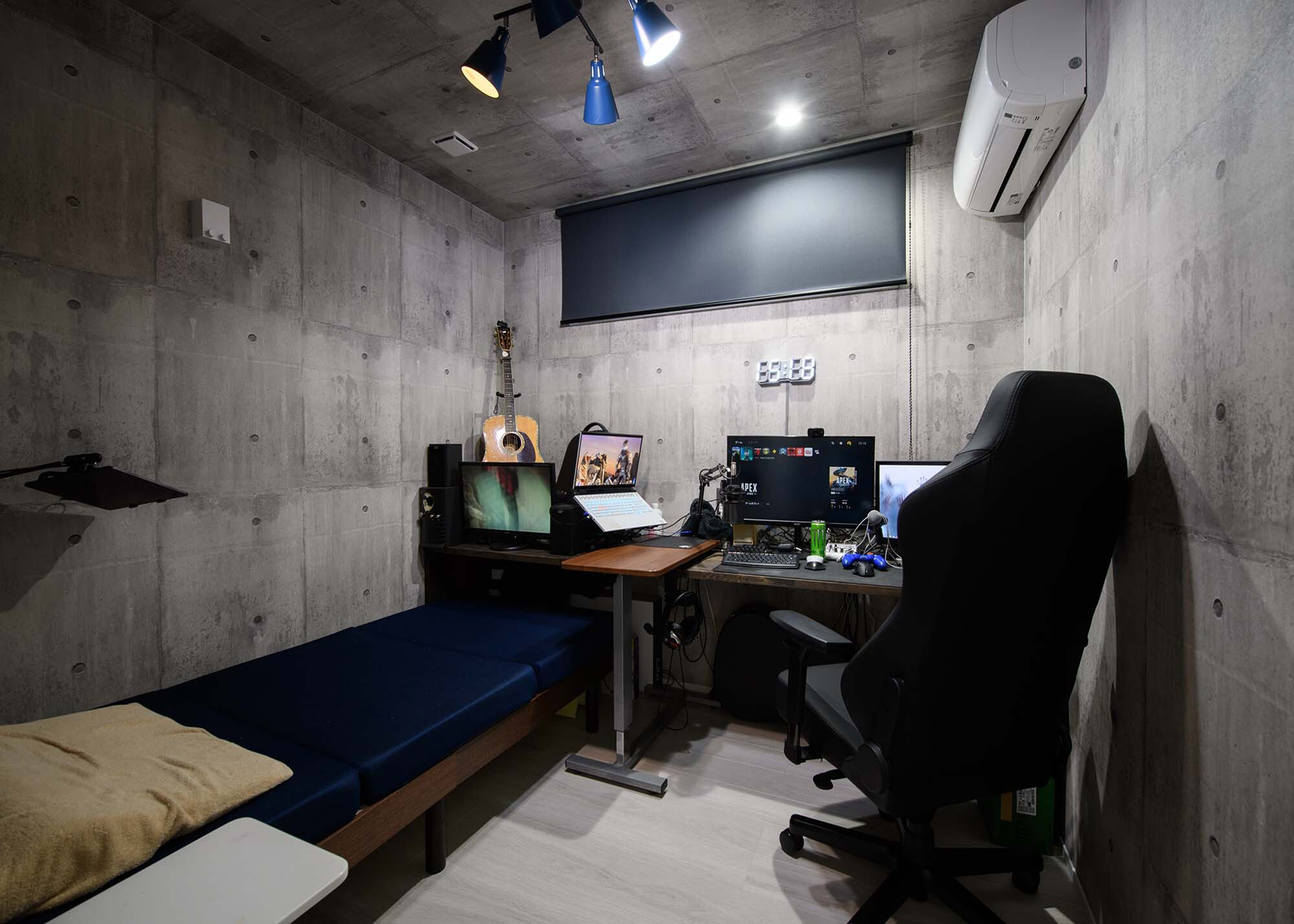 平屋建築ブルーハウス【デザイン住宅、間取り、建築家】ご主人の趣味部屋は、コンクリート打ち放し風のクロスでインダストリアルに演出。横長の窓にはネイビーブルーのロールスクリーンを設置し、仮眠用のベッドも設けた
