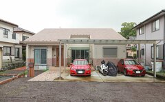 シンプルでスタイリッシュな住宅の外観。駐車スペースには二台の車が停められており、暮らしやすさを提供する設計