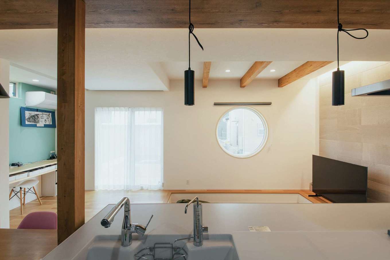 子育て安心住宅 Design Craft Office【デザイン住宅、収納力、間取り】キッチンに立つと正面に円窓が見える。空間に丸を取り入れたことで室内の雰囲気がやわらぎ、家族の団らんの場にふさわしい空間が叶った