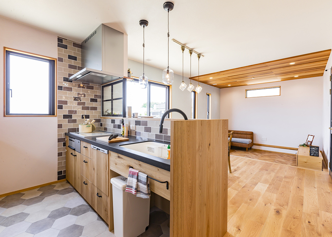 フルオーダーの木製キッチンは、ゴミ箱を置くスペースまで計算された使い勝手のいいデザイン。壁のタイルはご主人が貼ったもので、木の風合いによく馴染む