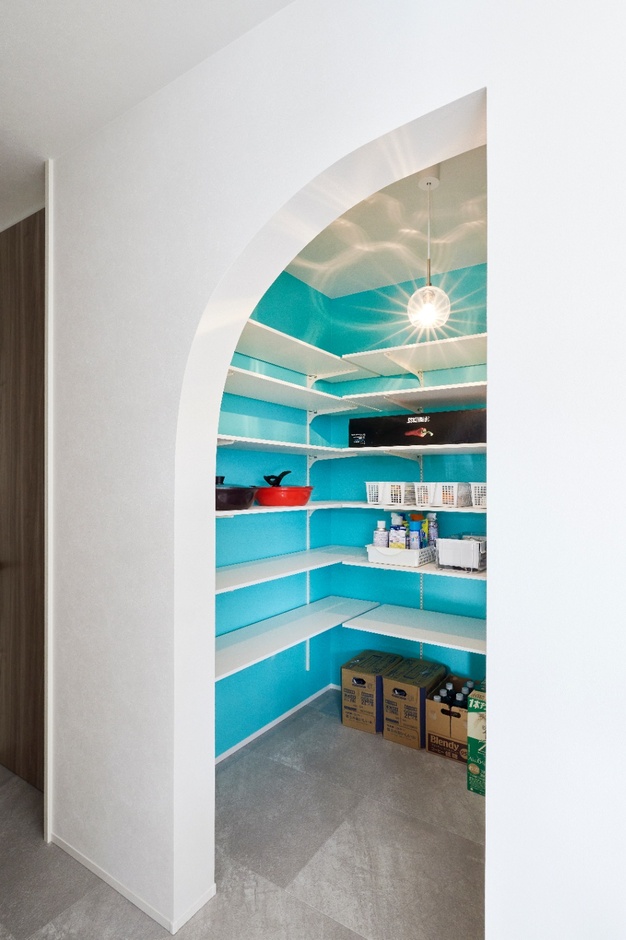 Rの垂れ壁とアクアブルーのアクセントクロスが特徴のパントリー。ペンダントライトの影がやわらかく広がったこだわりの空間。