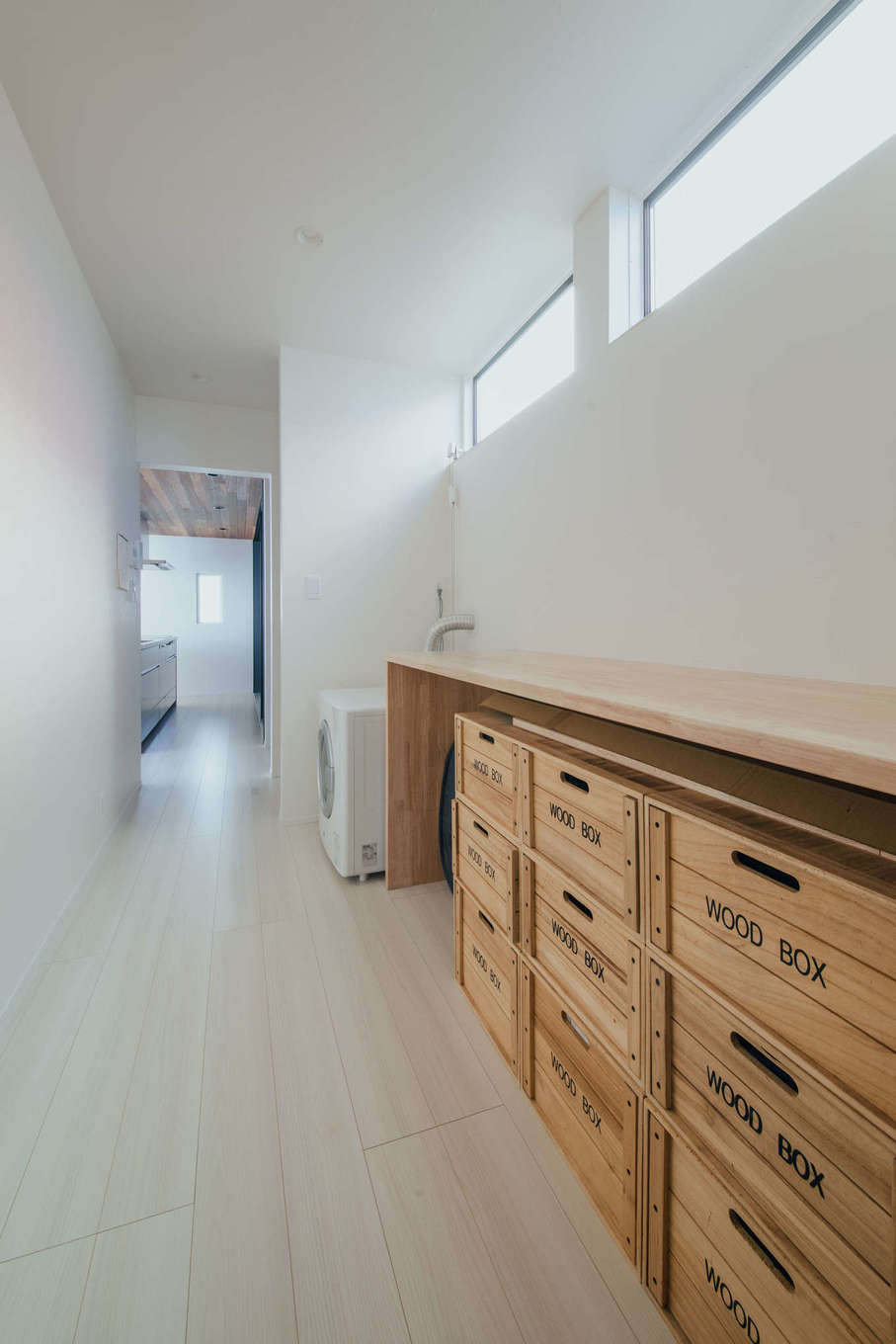 ハウスコネクト【デザイン住宅、ペット、平屋】キッチンからパントリー、ランドリールーム、ウォークスルークローゼット、主寝室までが一直線につながる動線。収納BOXの大きさに合わせて多目的に使える棚を造作した。ハイサイドライトからの光が北面でも十分な明るさをもたらす