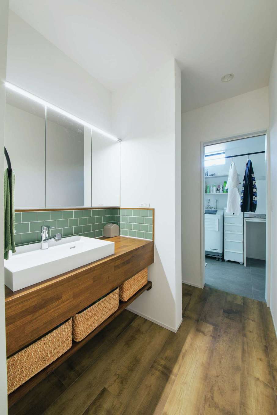 内田建設【デザイン住宅、子育て、間取り】玄関から洗面室、脱衣室へと行き止まりなしでつながる家事ラク動線。洗面台は造作でグリーンのタイルがアクセントに