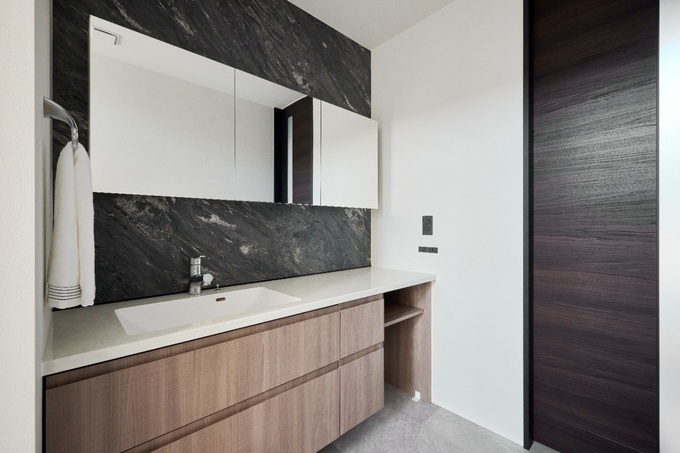 通路にある洗面台はどこからでもアクセスしやすい間取りになっている。洗面背面の大理石調が目を引き、ホテルライクな洗面空間を演出。