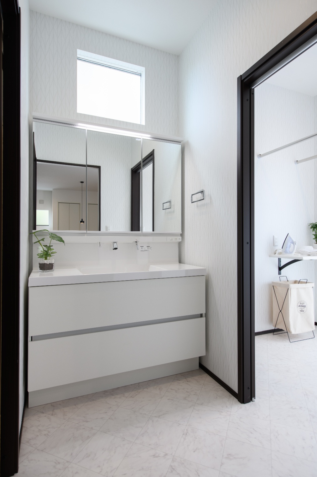 Sus∞Eco Home（サスエコホーム）｜シンプルでモダンな洗面スペース。大きな鏡が設置されており、朝の時間を快適に過ごせるデザイン。収納もしっかり備え付けられている。