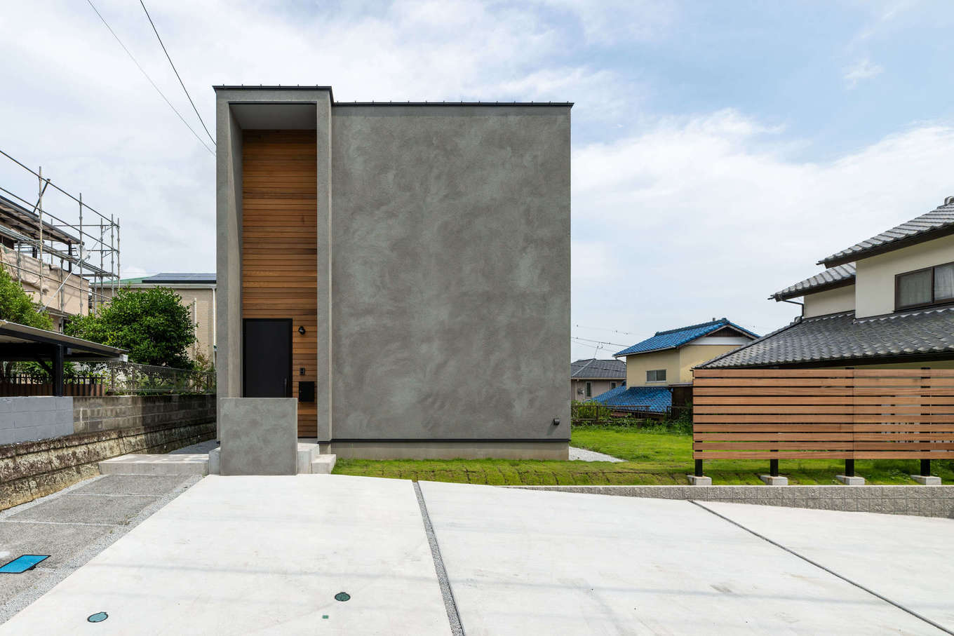 ハウスプラン（R＋house沼津・富士）【デザイン住宅、収納力、建築家】窓の無い大らかなマーブル模様が印象的なグレーの外観は、玄関ポーチに2階分の高さの庇を設けて浮き上がらせた長方形のラインがクールでスタイリッシュ。一部に張られた木のぬくもりが、やさしくアクセントを添えている