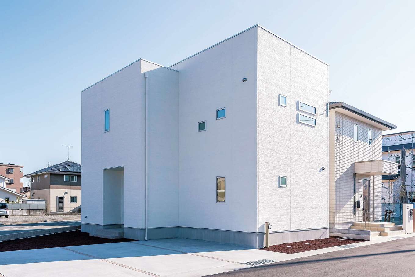 アフターホーム【1000万円台、デザイン住宅、間取り】青い空に映える真っ白な外観。リゾートのシーサイドを見おろす丘に立つ、豪邸や高級コンドミニアムのようなイメージでプランニング。ガラス部分には遮熱効果の高いフィルムを採用。中からの視界ははっきり、外部の視線はシャットアウトするマジックミラー効果で、プライバシーにも配慮。天気の良い日は青空を映しこみ、白い壁とのコントラストもきれい