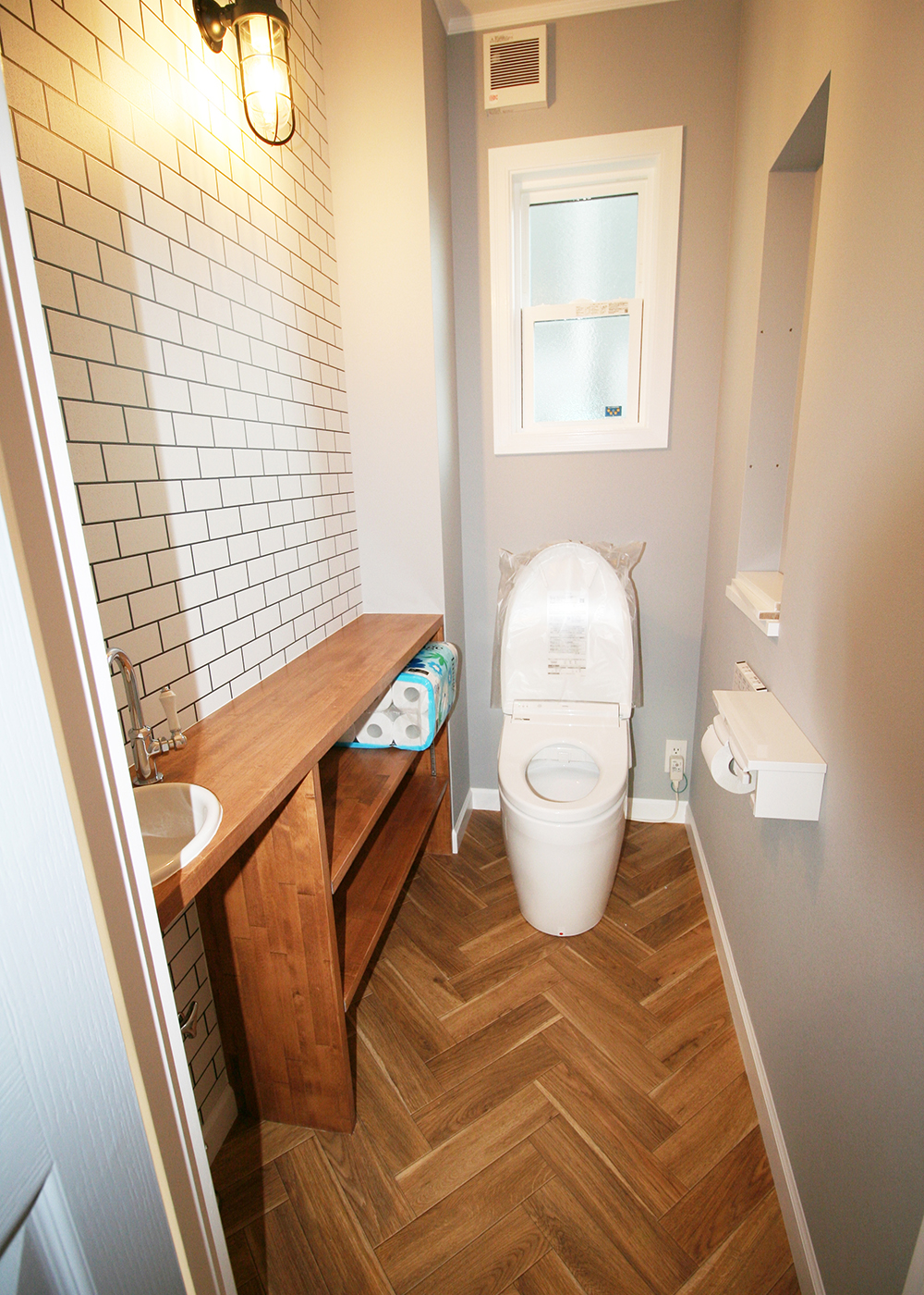 メープルホームズ伊豆 (吉村工務店)【輸入住宅、ペット、ガレージ】トイレの床はクラシカルなテイストを演出するヘリンボーン柄を採用。マリンランプの雰囲気ともマッチする