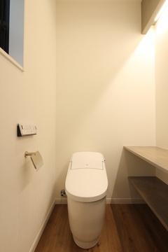 シンプルで清潔感のあるトイレ空間。自然光が入る窓が設置され、落ち着いた雰囲気を感じさせる設計が魅力的である。