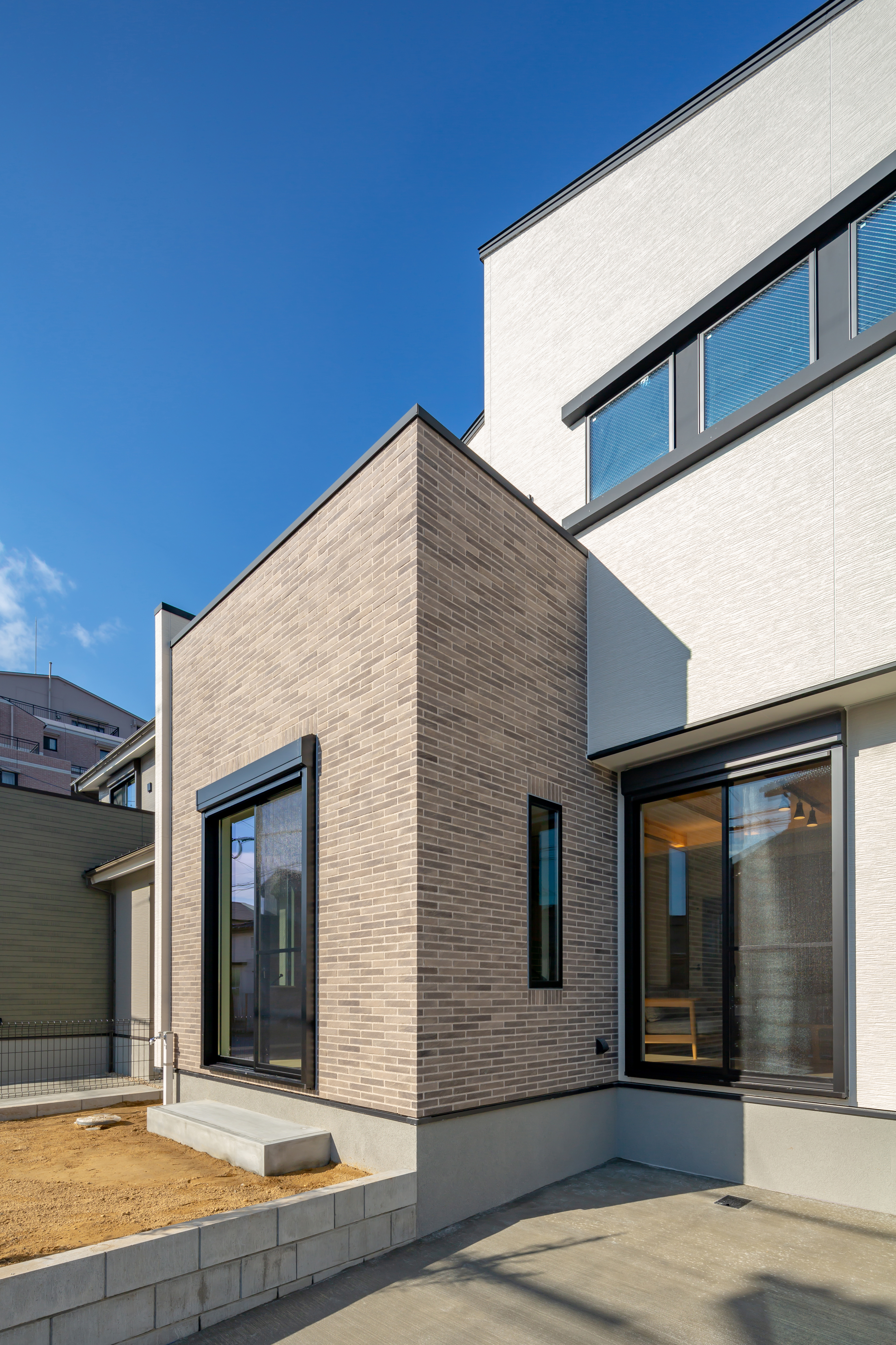 ムニカデザイン（まほろばホーム）｜南側道路の日当たりの良さを最大限に生かし素焼きのグレーのタイルを施工した外壁は、可愛らしさと重厚感のハイブリットな印象に仕上げました。