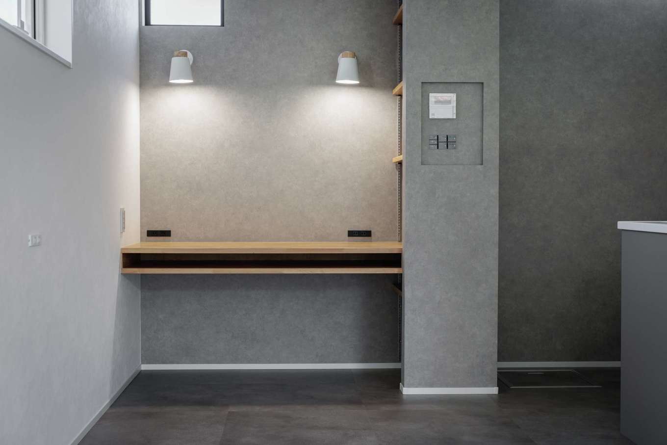 tact design firm【デザイン住宅、子育て、間取り】キッチンから見える場所に設けた子どもたちのスタディコーナー。照明とコンセントを2つずつ設置して、仲良く勉強できるようになっている。隣家で咲く桜の美しい借景を楽しめるよう、窓を大きめに。袖壁にテレビの配線やPCのルーターなどをしまい、リビングをすっきりと見せている