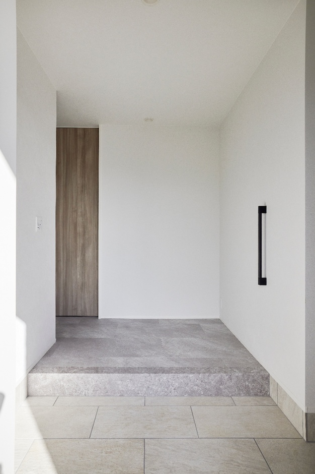 愛犬が通る床には全てフロアタイルを使用し、耐久性と掃除のしやすさを優先した実用的な空間。シンプルな玄関が落ち着いた印象を与える。