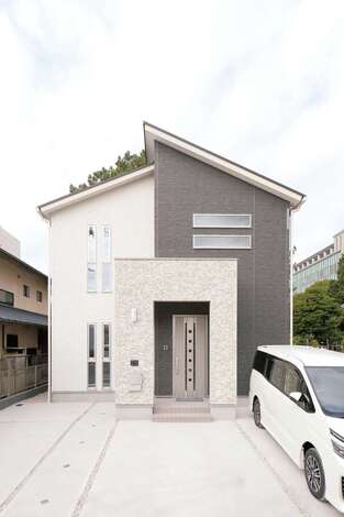 ツートンカラーの外観。シンプルモダンな外観は、白とグレーのツートンカラーが上品な印象を与える。玄関回りのみタイル調のサイディングを貼って高級感を演出。ソーラーパネルも搭載