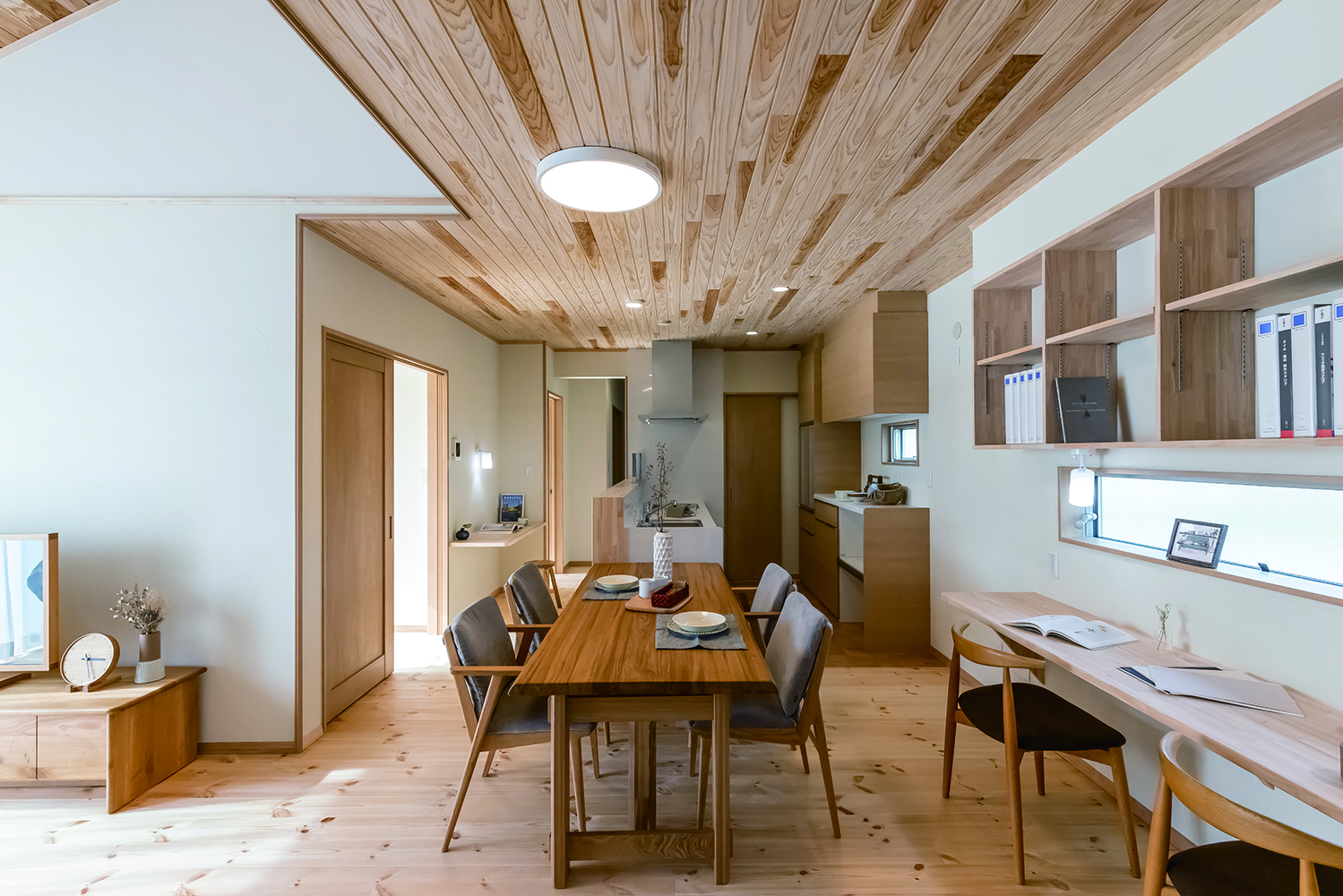 住まいるコーポレーション【自然素材、省エネ、平屋】キッチンとテーブルを横一列に並べたダイニング。窓際のスタディコーナーは、横並びで3人は座れる広さを確保。壁の上部には教科書や参考書などをしまえる書棚も用意した