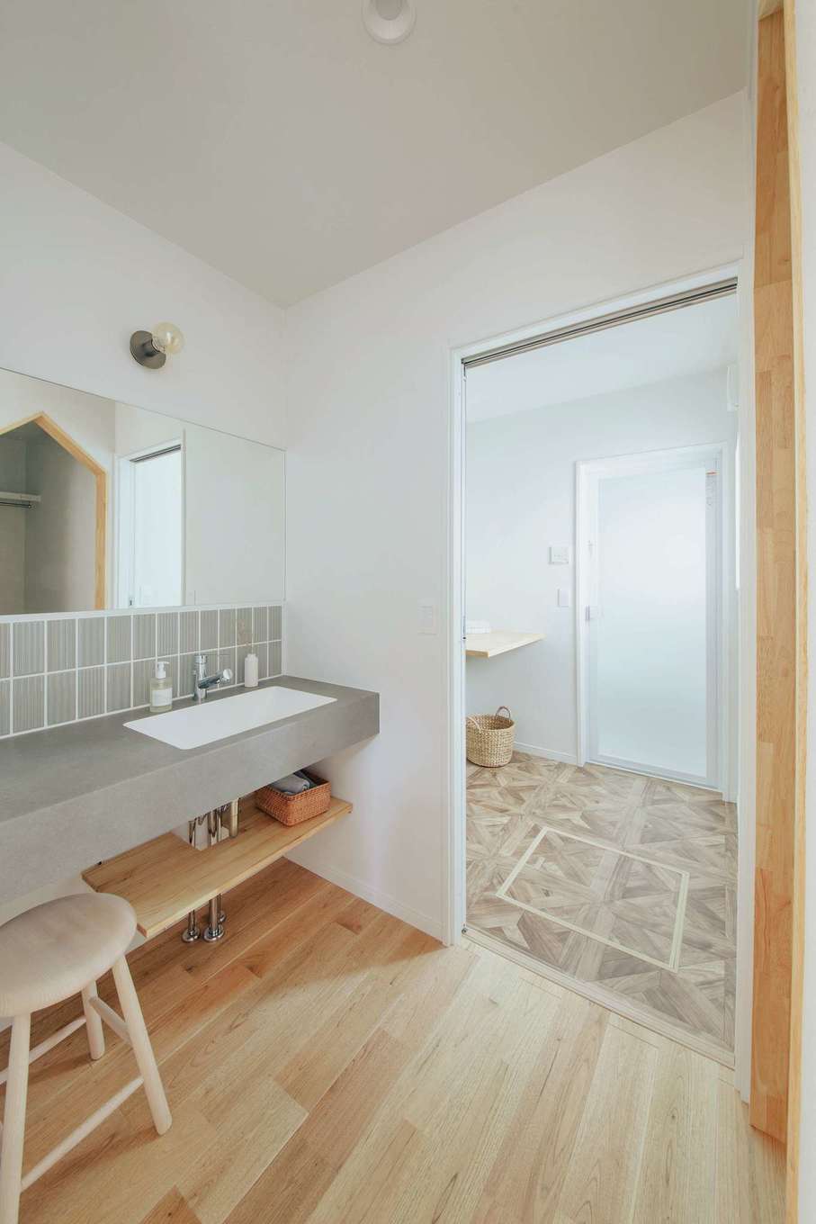 ほっと住まいる【自然素材、間取り、インテリア】グレーのタイルがおしゃれな洗面台は、鏡も大きく使い勝手がいい。後ろにファミリークローゼットがあり、洗濯後の衣類をすぐに収納できる