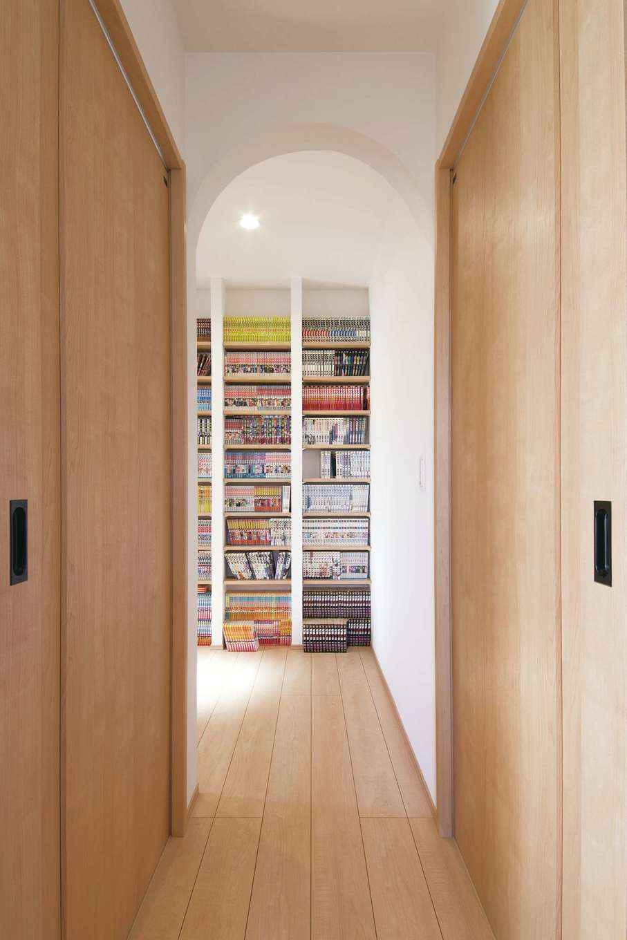 コットンハウス【子育て、省エネ、間取り】2階の納戸はコミック本が大好きなご主人の蔵書を収納するライブラリーに。造り付けの本棚は地震でも倒れる心配がない。アーチ型の入り口がアクセント