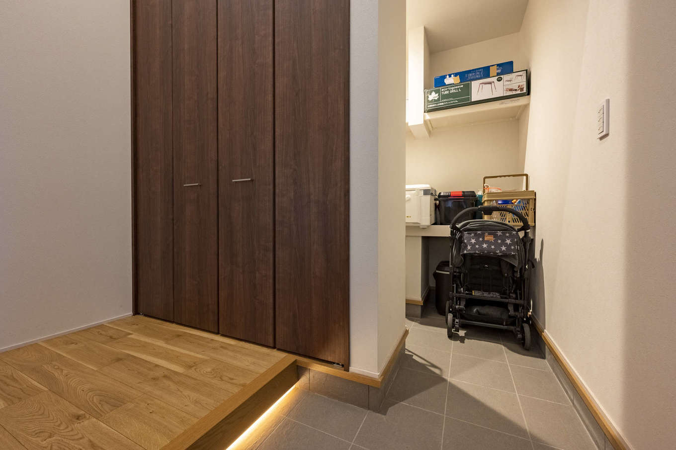AQURA HOME（アキュラホーム）【デザイン住宅、収納力、間取り】吹抜けの玄関ホール。ベビーカーをはじめ、キャンプ用品、ゴルフバッグ、釣り道具などもすっぽり収納できる土間収納を備えた。框を間接照明で照らして柔らかな明かりの雰囲気に