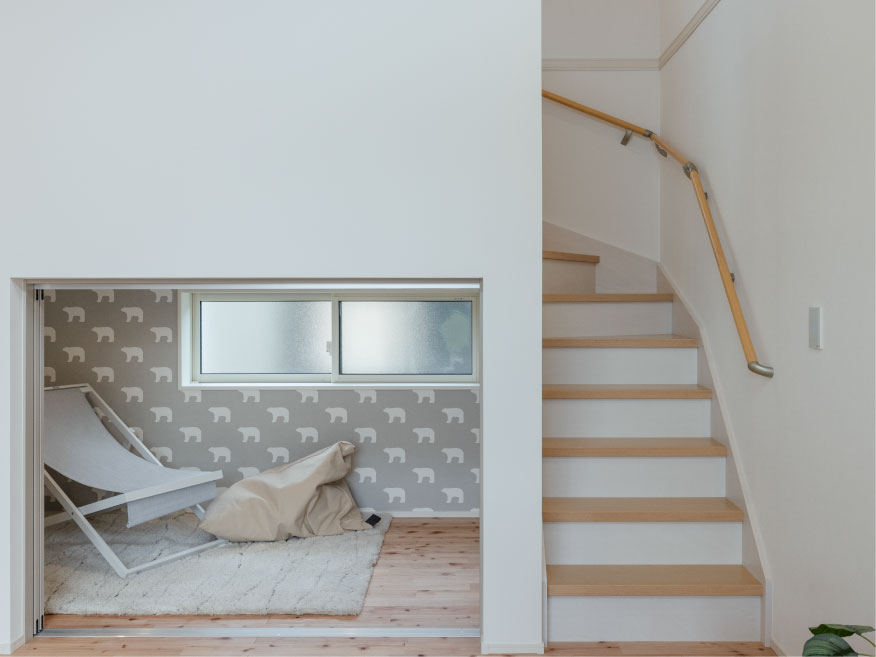 ヘスタホーム｜階段下を有効活用した、多目的な広すぎ収納スペース。可愛らしい柄のクロスと木目調の床が、温かみのある空間を演出。小窓からの自然光で明るく、開放感も確保。