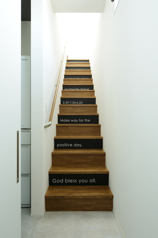 階段の蹴込（けこみ）板は一段置きに黒い板にして、白字でペイントを施した。家族のラッキーナンバーや、好きな言葉を英語で記してある。ご主人のグッド・アイデアが活かされたスポット