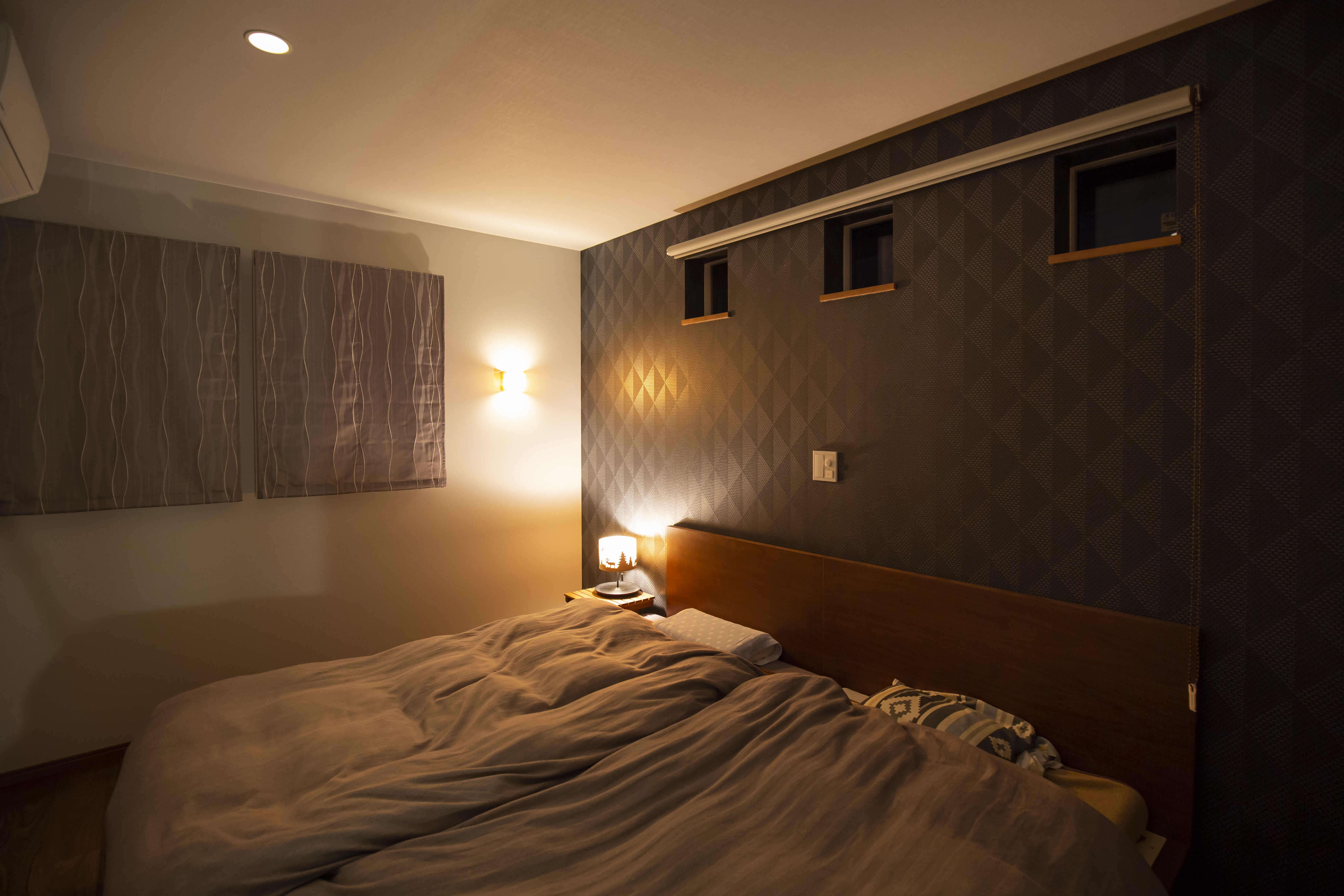 トヨタウッドユーホーム｜落ち着いたトーンの壁紙を間接照明が柔らかに照らす寝室。