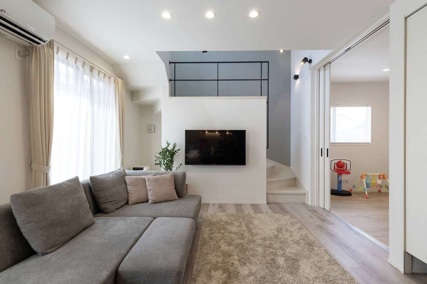 HAPPY HOUSE（山田工務店）【デザイン住宅、間取り、インテリア】右のプレイルームや窓から出入りするウッドデッキも、LDKから目が届く距離に。TV奥のリビング階段は、吹き抜けで2階とゆるやかにつながる