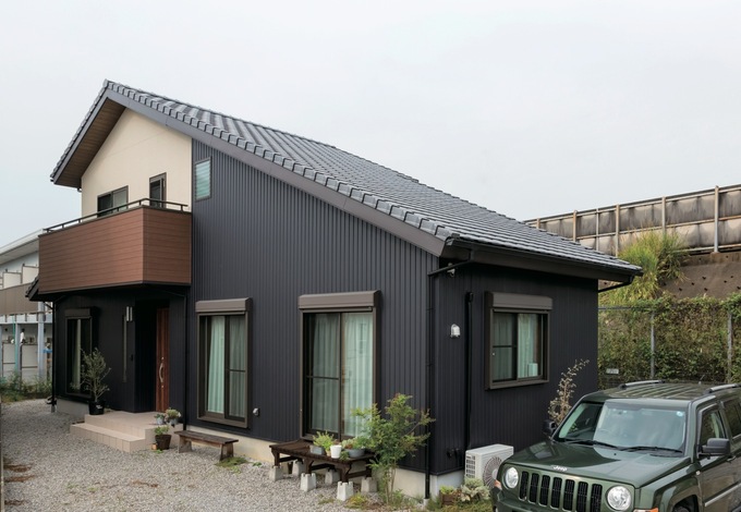 平屋をイメージした片流れの大屋根が素敵。ブラックのガルバリウムと木がバラン スよく調和している。ウッドデッキ代わりのベンチはご主人のセルフビルド