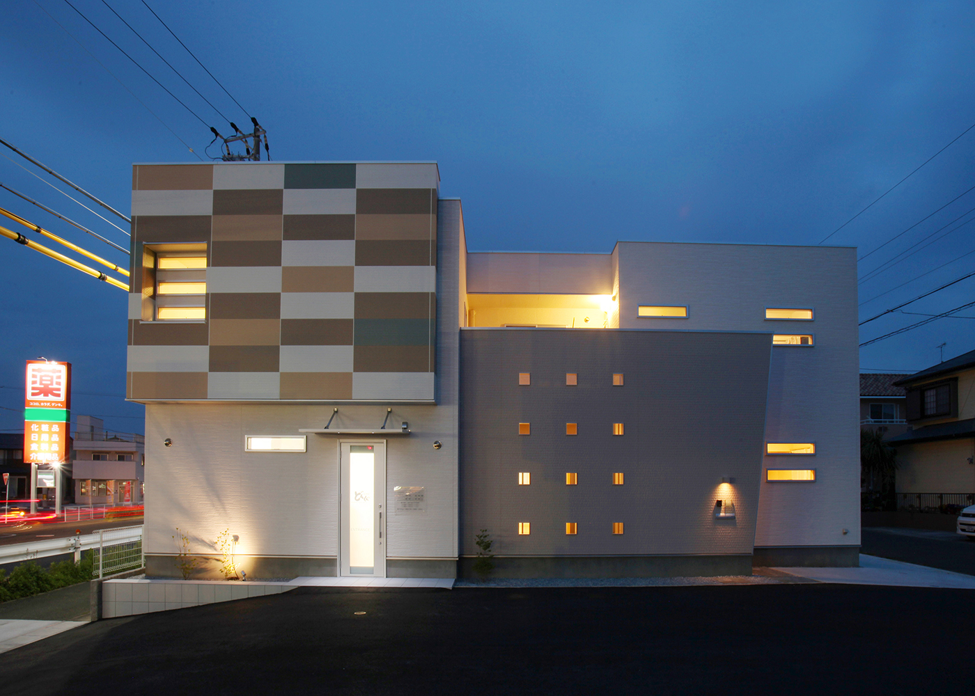 丸昇彦坂建設【デザイン住宅、間取り、インテリア】外観のユニークさは夜間も魅力を失わない。飾り壁の穴や窓から零れる照明の光、スポットライトが外観を彩る