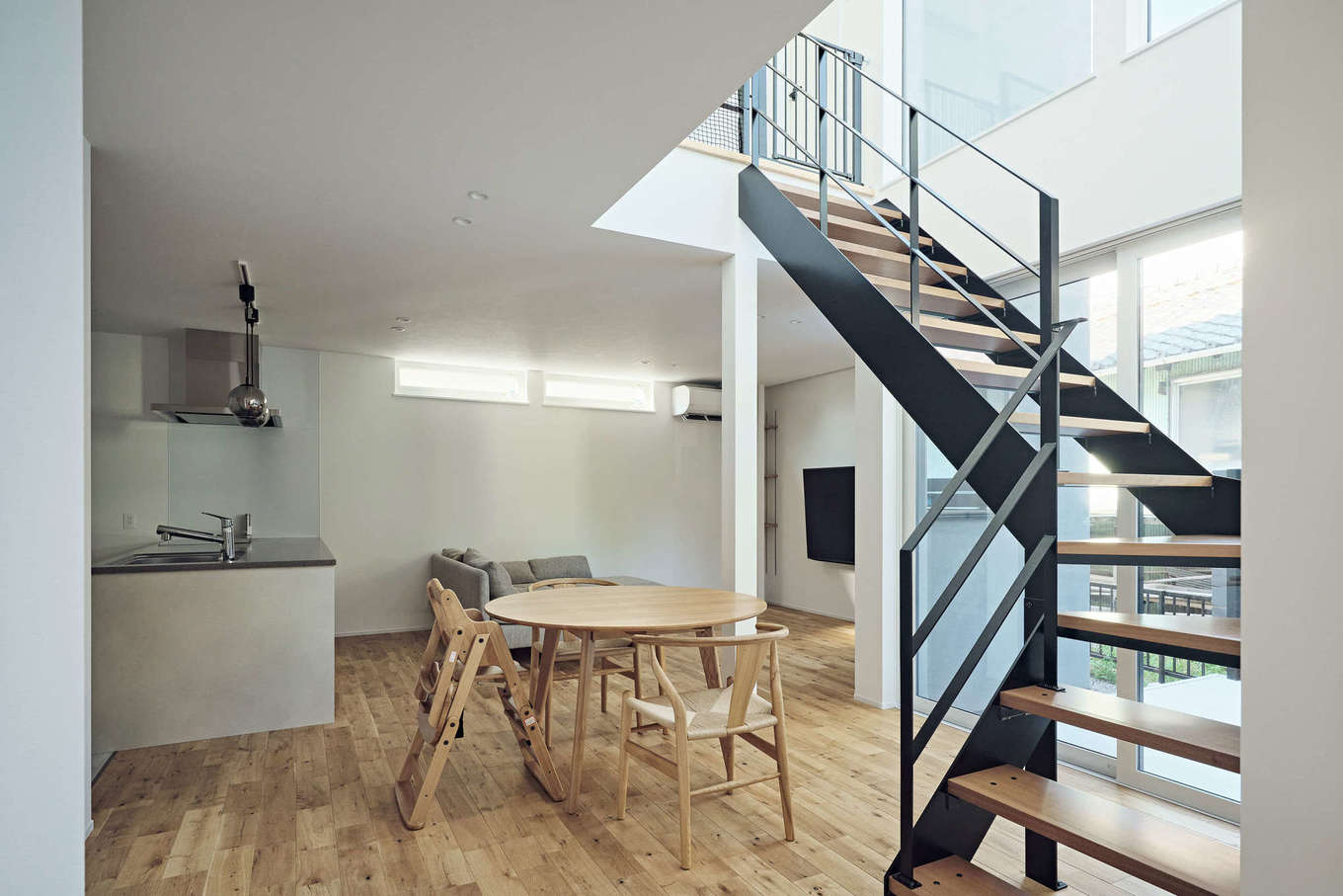 平屋建築ブルーハウス【デザイン住宅、建築家、平屋】階段部分は吹き抜けを採用。上下に大きな窓が設置され、室内全体に光と開放感を届けている。鉄骨のストリップ階段は、間取りに合わせて角度を付け、空間を有効に活用している