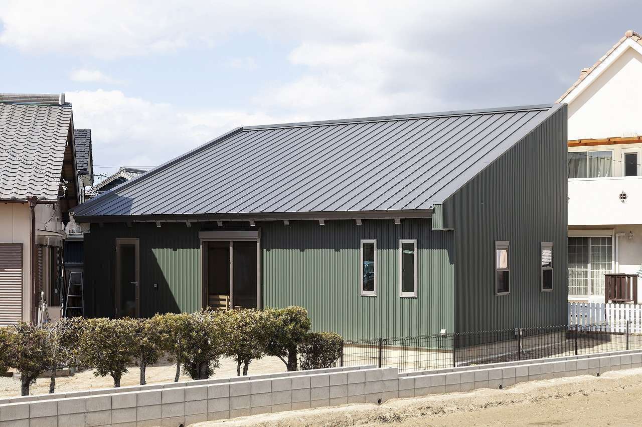 明城【1000万円台、自然素材、平屋】実家の敷地内に建てたK邸。日照と風向きのシミュレーションを実施して建物を配置した。外壁は夫婦の好きなモスグリーンのガルバリウムを採用。大胆な片流れの屋根が印象的