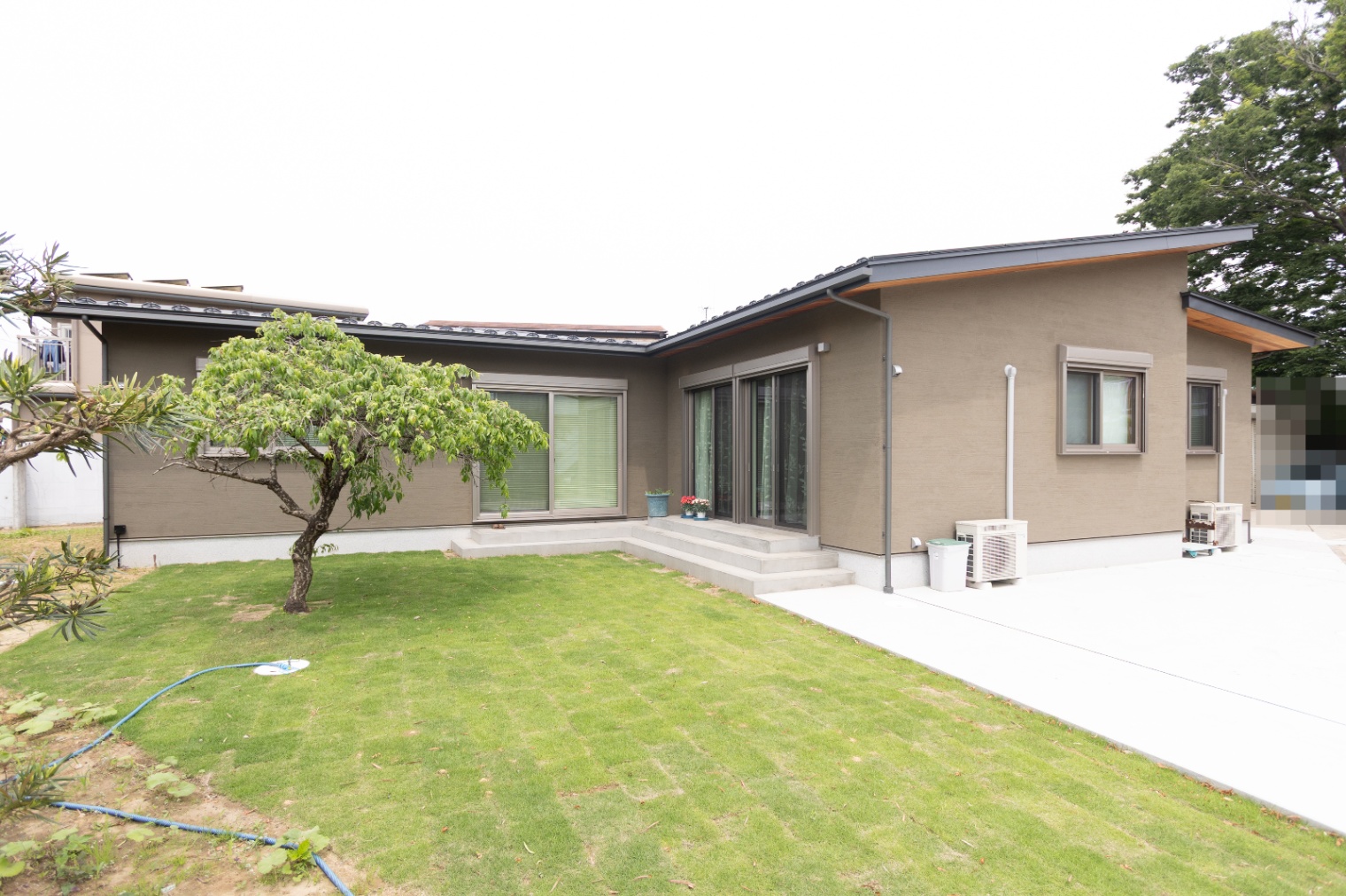 ハルクホーム｜広々とした庭に面した平屋の住宅外観。シンプルで落ち着いたデザインが、周囲の自然と調和している。
