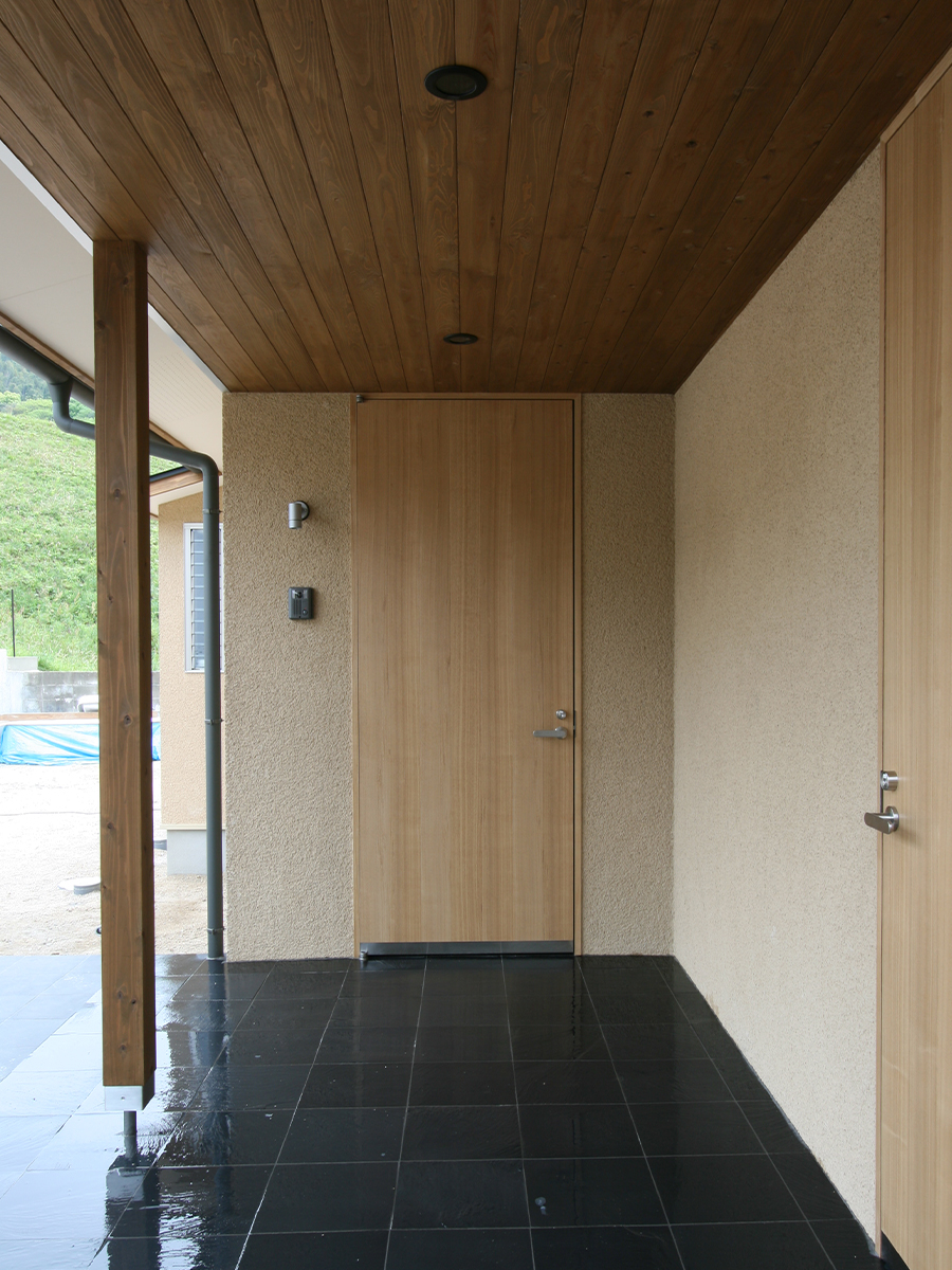 斉藤工務店｜自然素材を活かした玄関。木材の天井と石材の床が調和し、訪れる人を温かく迎える。シンプルなデザインがモダンな印象を与える。