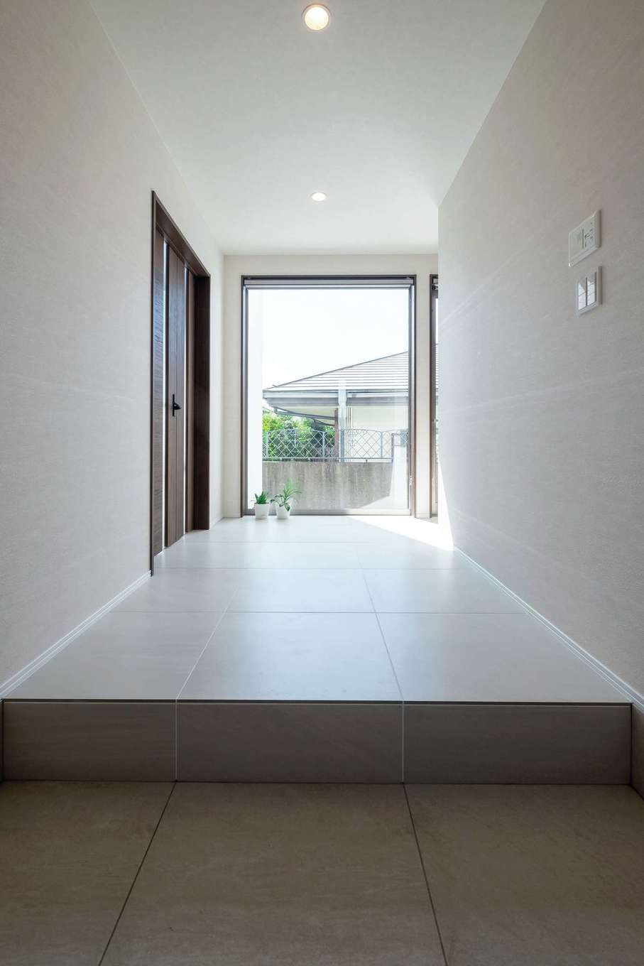 -delphi- デルフィ（藤井建築事務所） 【デザイン住宅、建築家、インテリア】大きなFIX窓の先へと目線が抜けていく、開放感あふれる玄関ホール。600mm角のタイルを採用し、高級感のある仕上がりに
