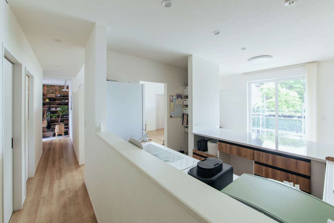 子育て安心住宅 Design Craft Office【デザイン住宅、趣味、平屋】プライベート空間と共有空間を仕切る廊下が、玄関から一直線に続く。コックピット型のキッチンは廊下に面しているため、家族がどこにいても様子がよくわかる