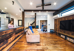 インドネシアチークの無垢床、ヘリンボーンの板張りの壁、焼き色を付けたラオスマツの腰壁と、個性ゆたかな木の表情に彩られたLDK。白い部分の壁は珪藻土塗りで、自然素材に囲まれた空間が心地よさをもたらしている