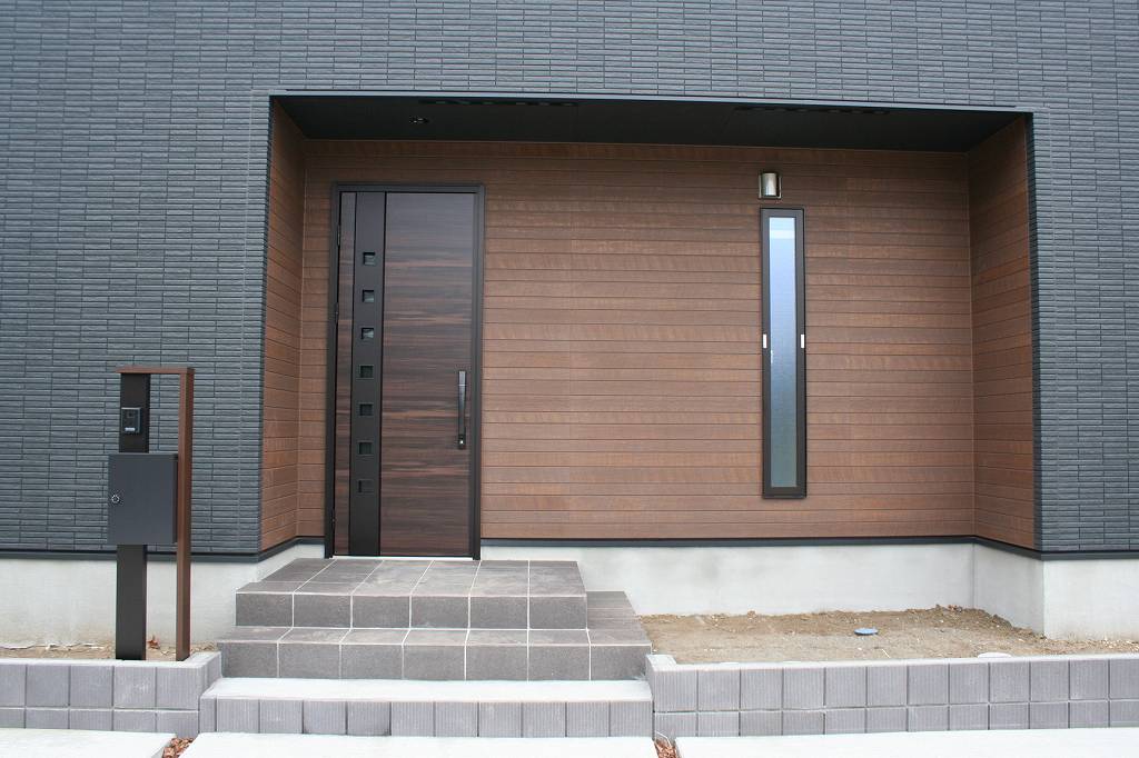 タムラ建築設計｜シンプルでモダンなデザインの玄関。洗練された木目の外壁がアクセントとなり、上質な空間を演出している。