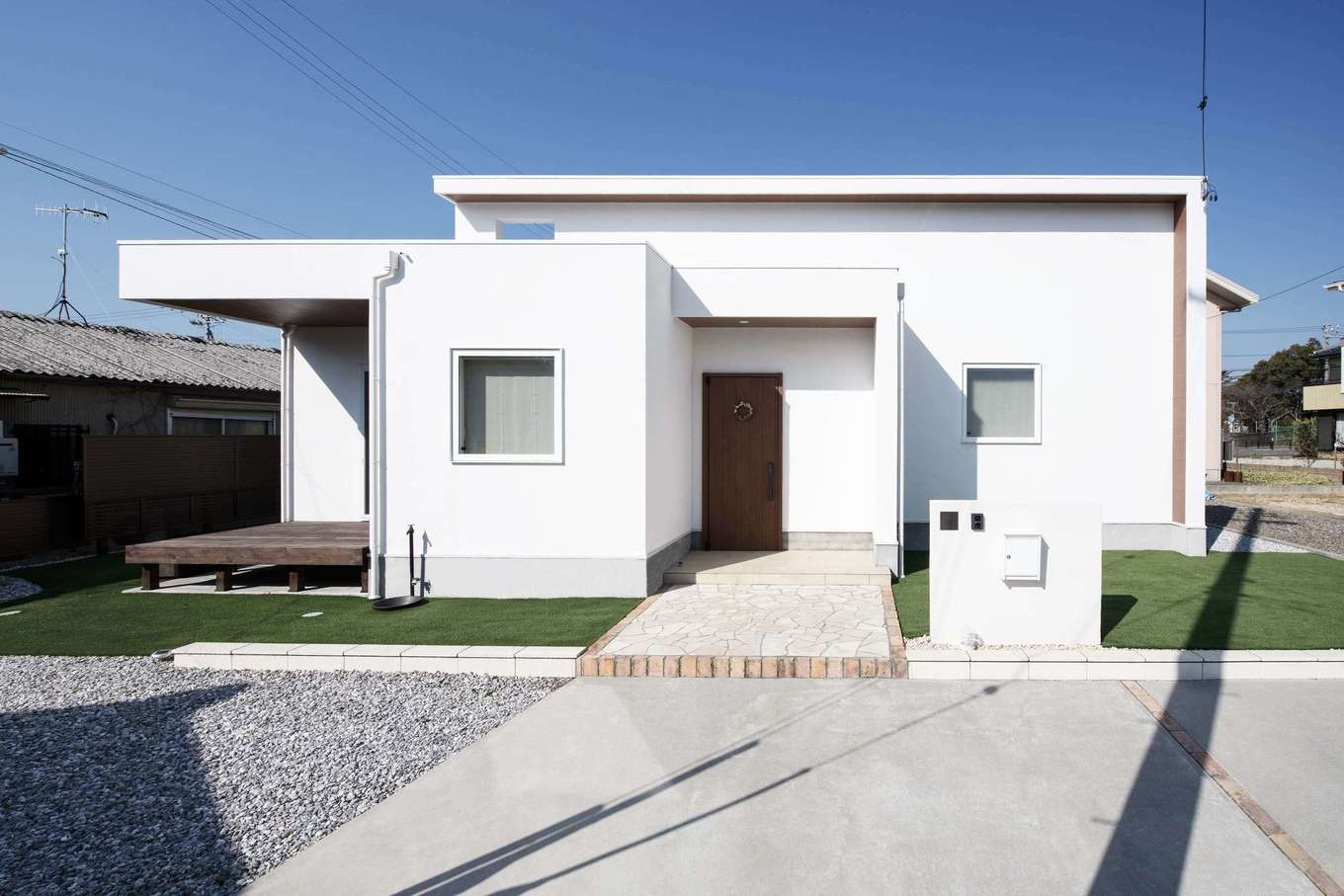 平屋建築ブルーハウス【デザイン住宅、子育て、平屋】バランスの取れた美しいフォルムがスタイリッシュな外観。白い塗り壁が上質感を醸し出す。ウッドデッキは子ども部屋に面して設けてあり、子どもが自由に行き来して、のびのびと遊べるように配慮されている